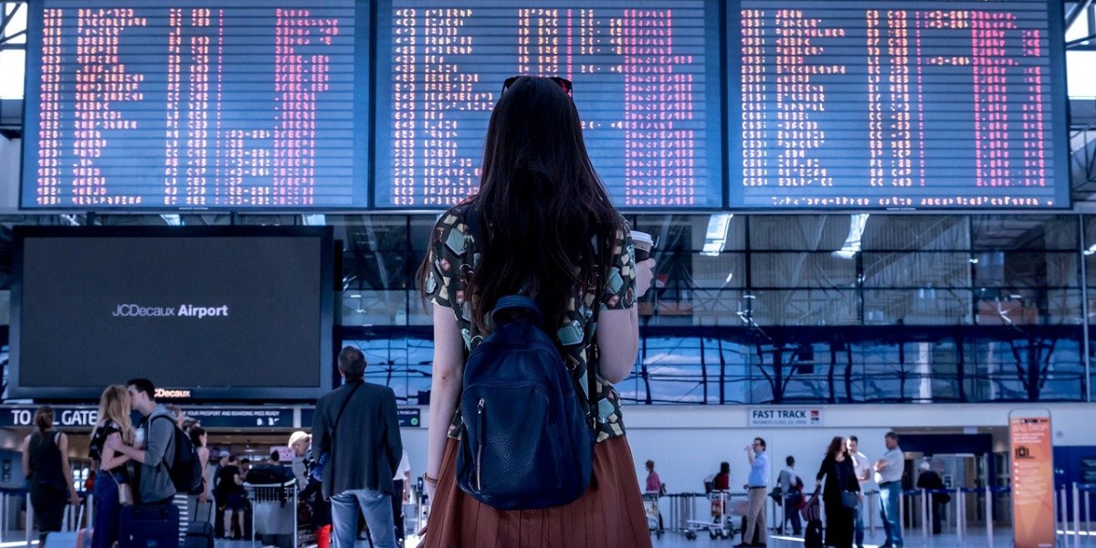 Woman waiting in front of departure screens on airport